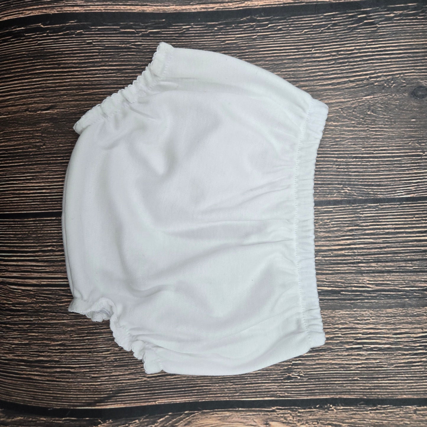 White baby bloomers on a wooden surface