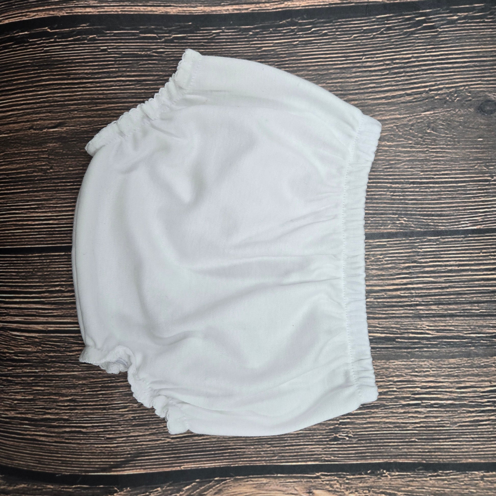 White baby bloomers on a wooden surface